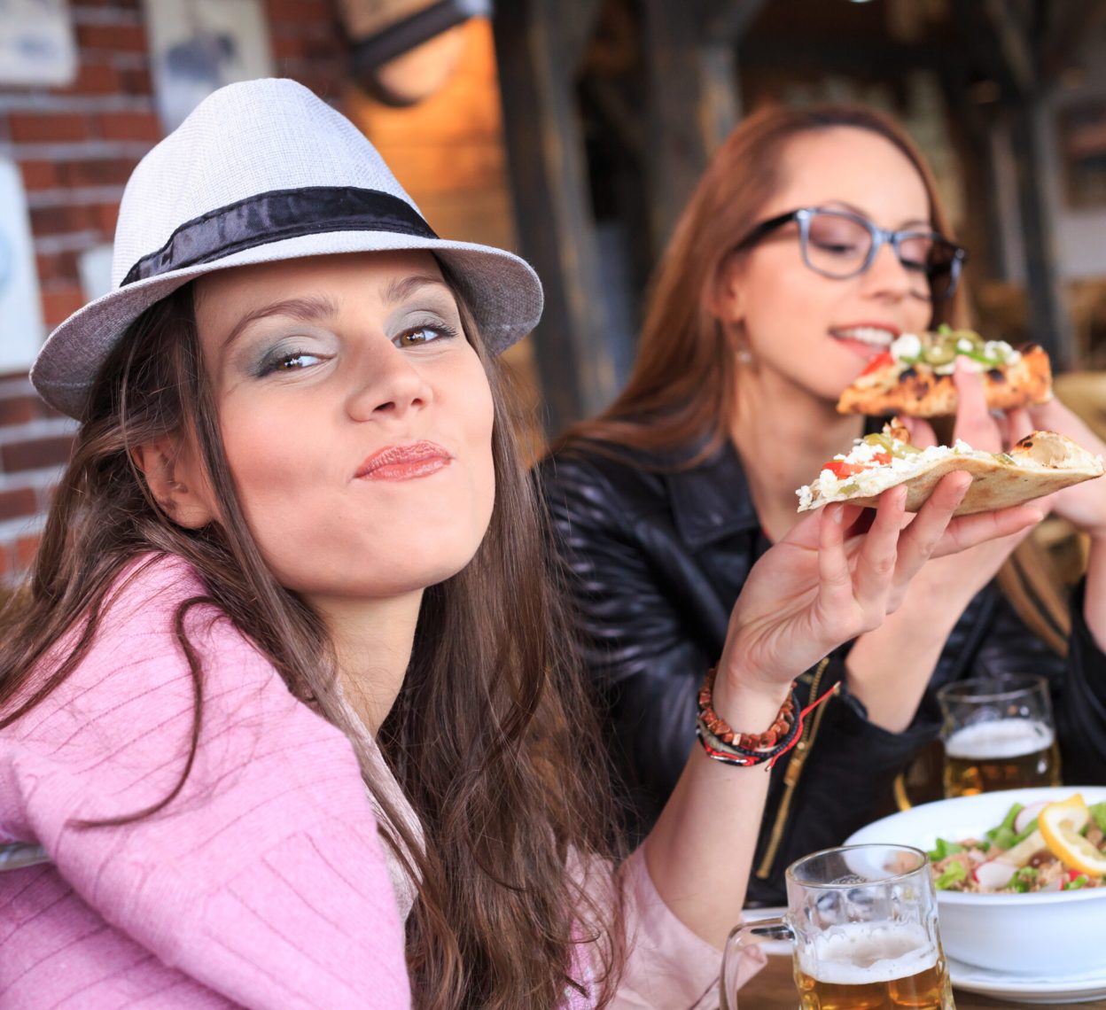 Young people eating pizza in restaurant, drinking beer.